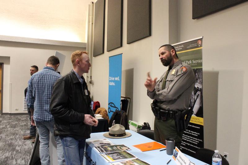 Employer at a career fair booth talking with a student
