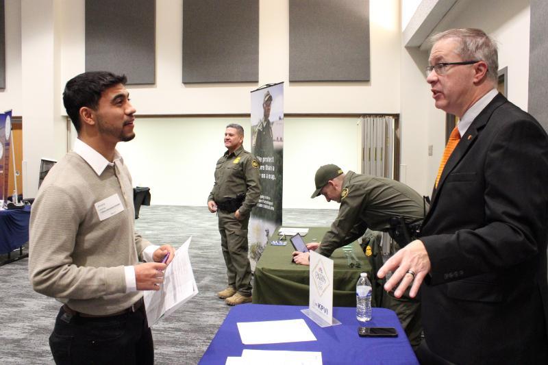 Employer at a career fair booth talking with a student