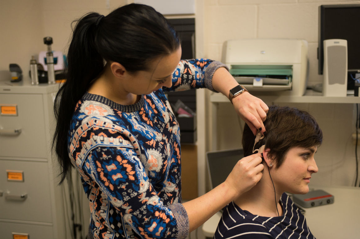 Audiologist placing a hearing aid