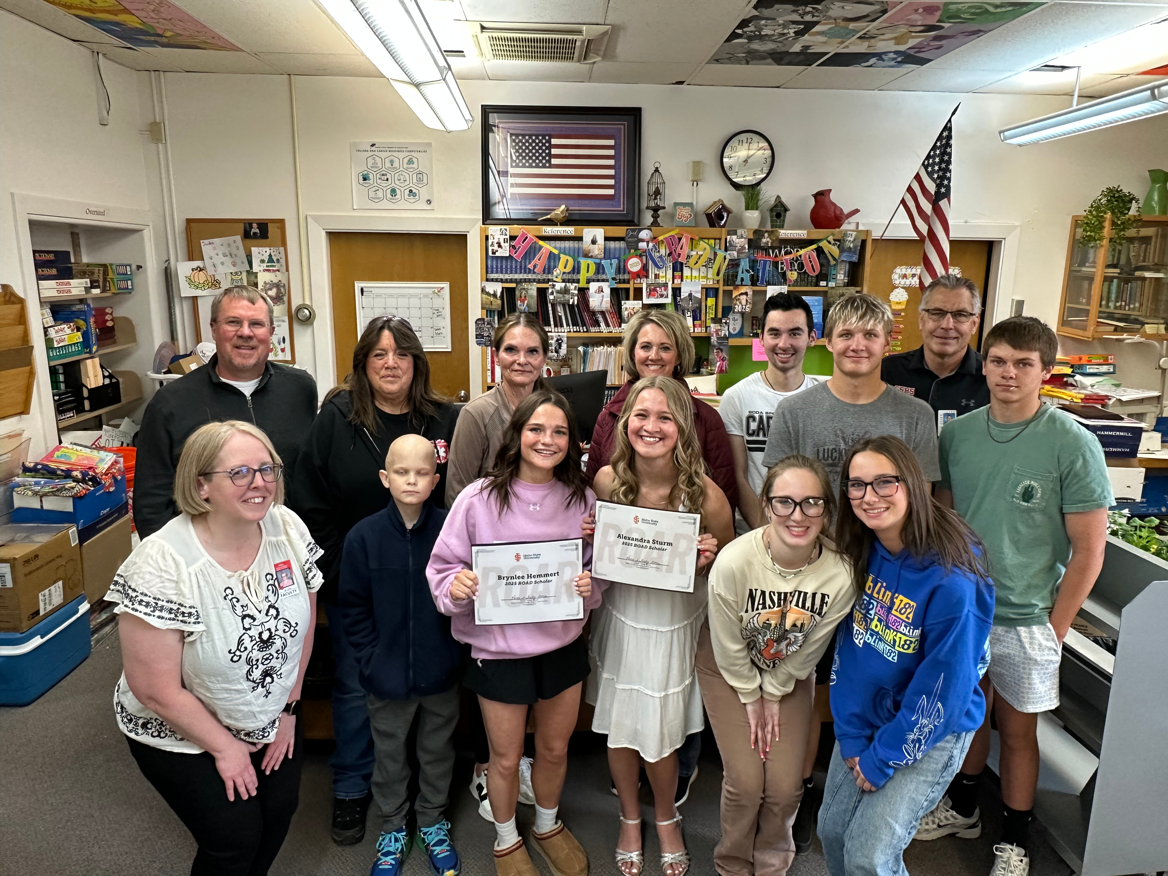 Two Soda Springs students holding awarded scholarships surrounded by teachers and peers