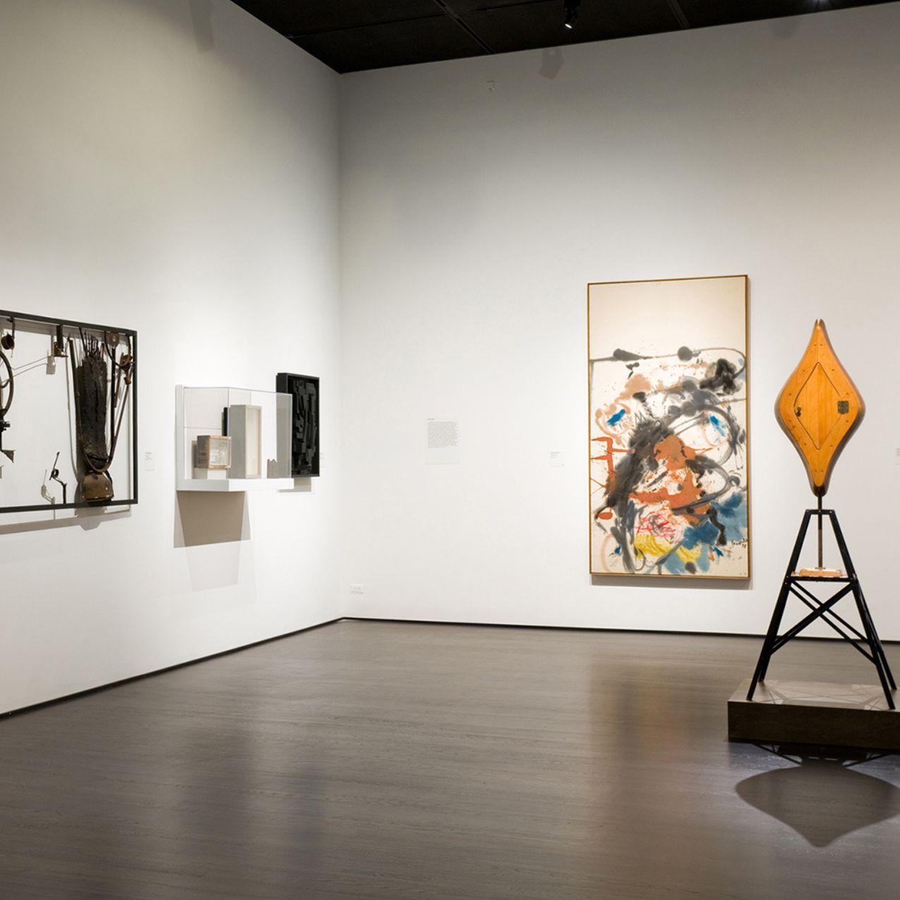 The art gallery at ISU. White walls, a few paintings are on the walls and there is a sculpture with an orange top,