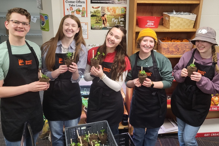 Five student volunteers holding potted plants