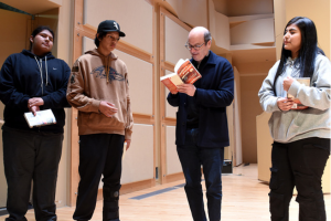 David Grann stand among 3 students. He's holding a book and signing it.
