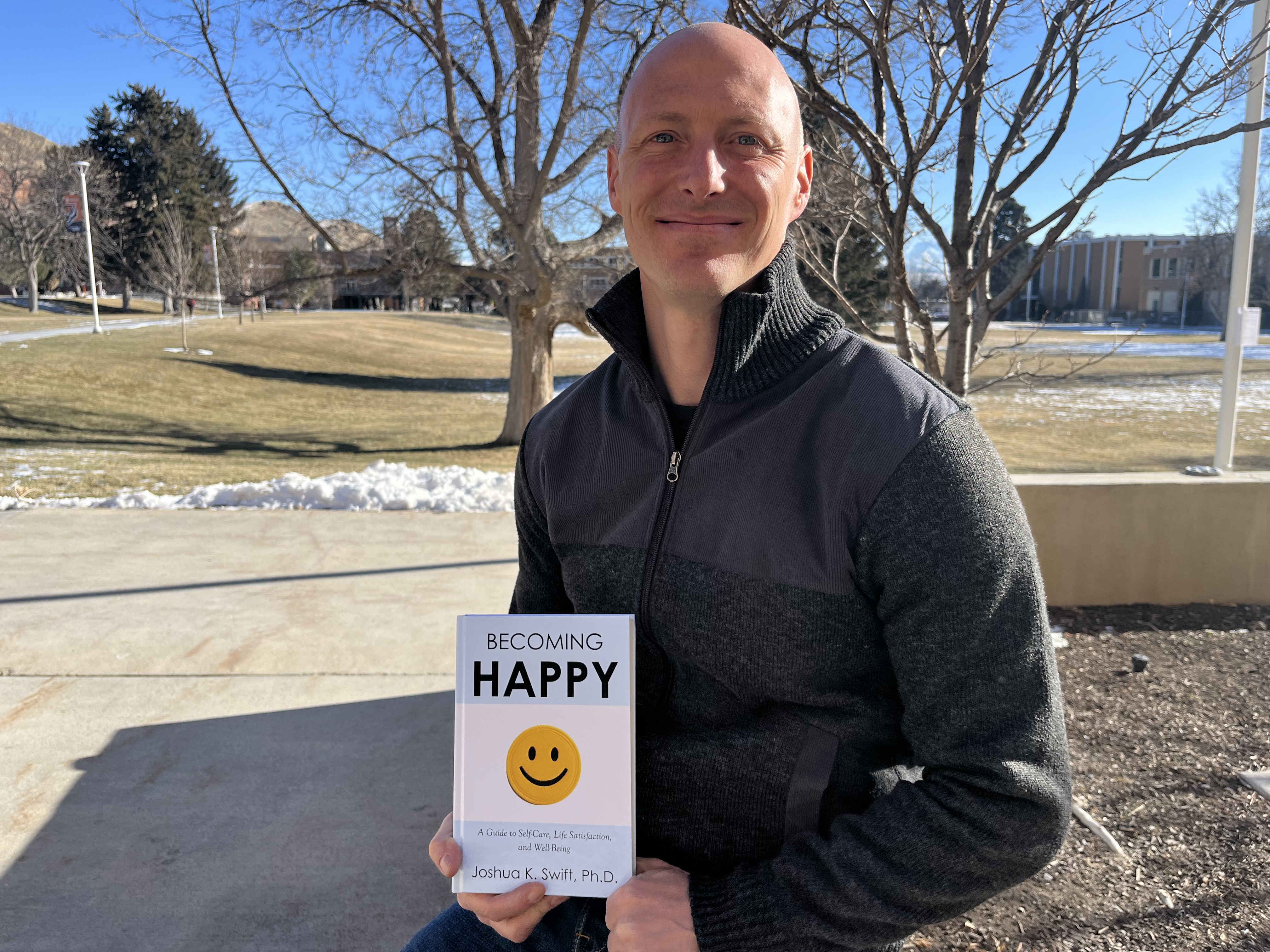 Joshua Swift holding his book titled 