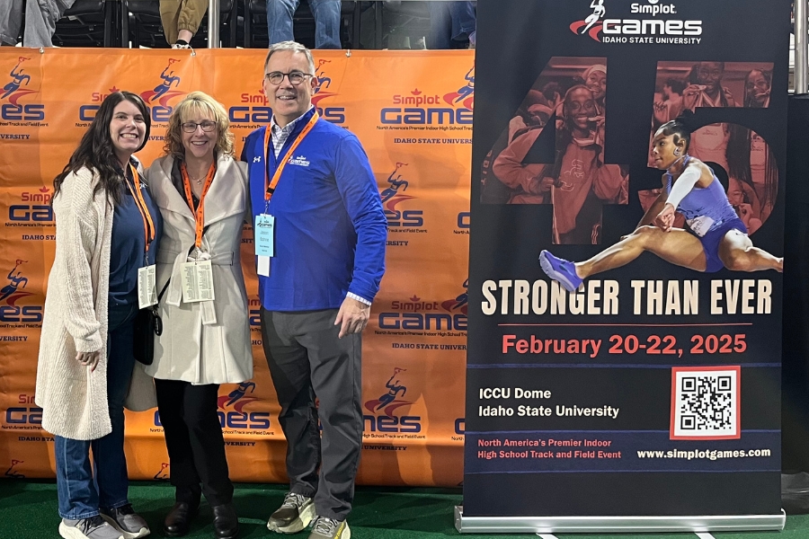 Melissa, Kandi, and Jason standing in front of the Simplot Games banner