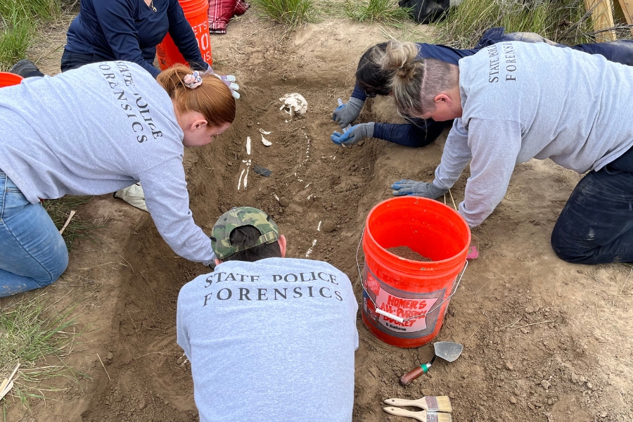 Five people on their knees around a dig site