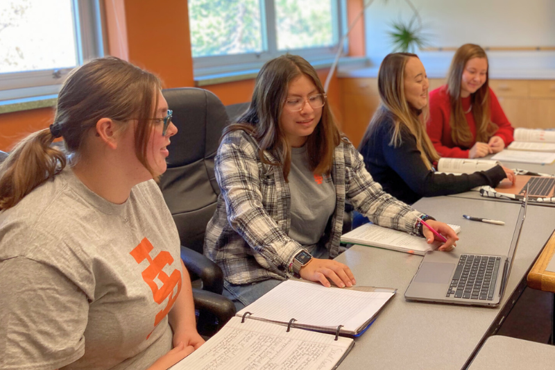 Four students sit at a table talking and studying