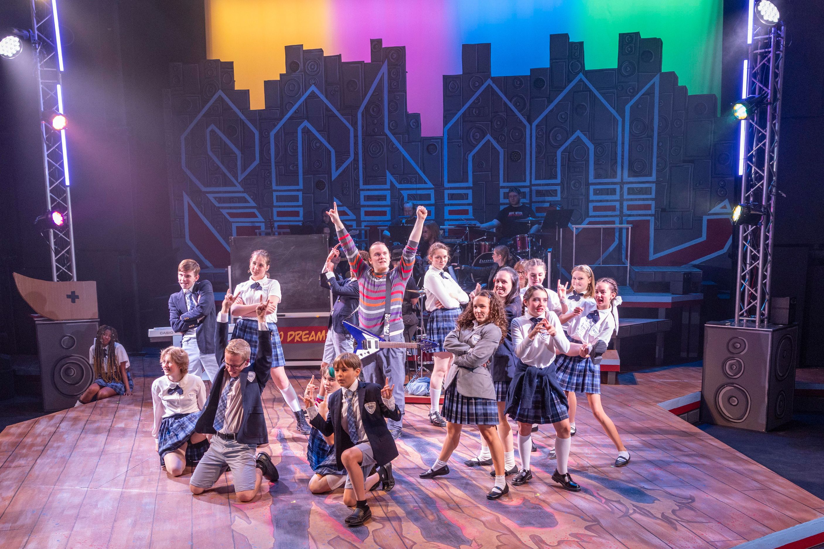 Cast of musical onstage with arms upraised