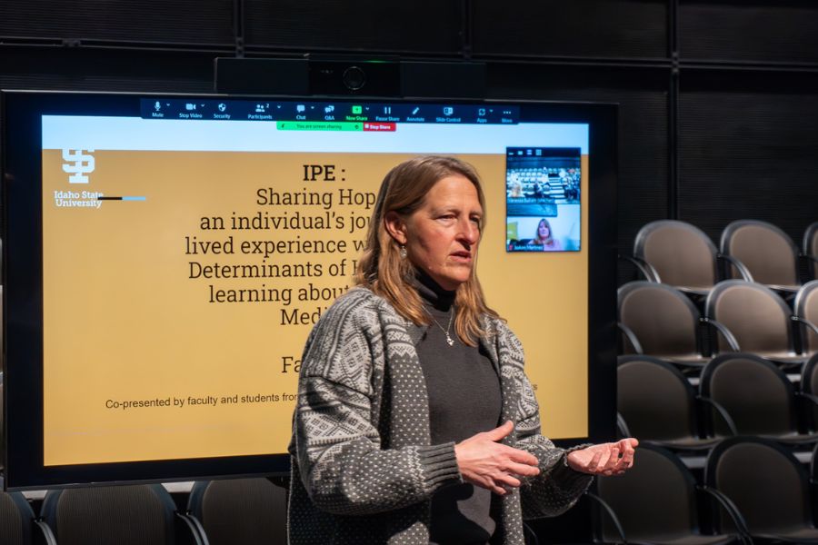 Paula Phelps presenting in front of a large TV screen with a powerpoint