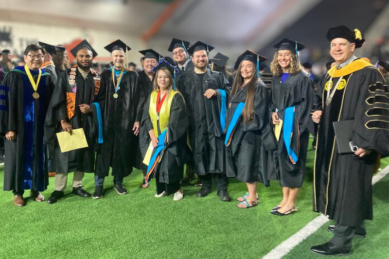 Students in graduation regalia pose for a group photo