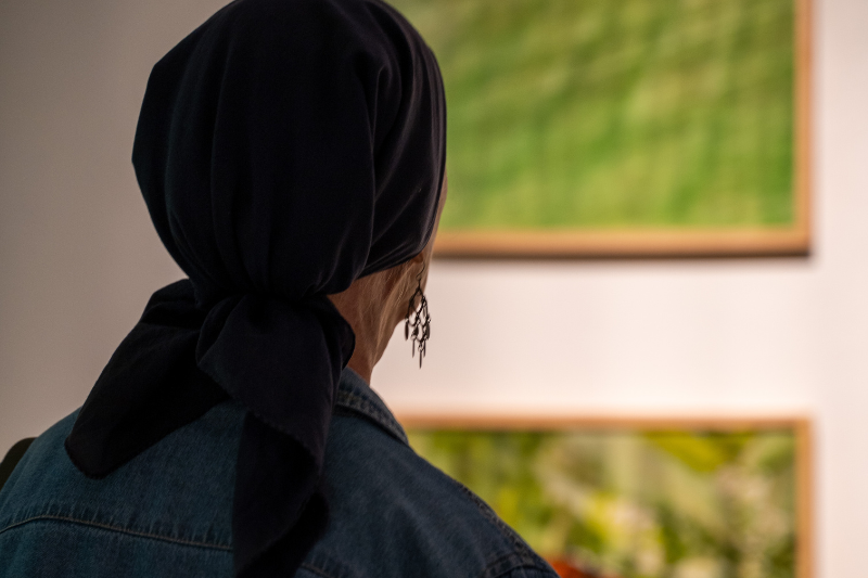 close up of a person from behind looking at artwork on a gallery wall