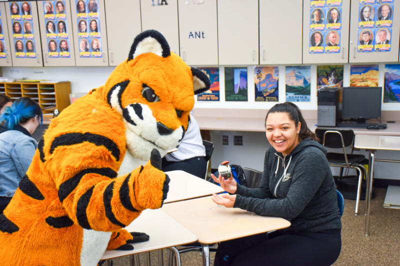 Benny the Bengal giving a thumbs up with a student holding a cupcake