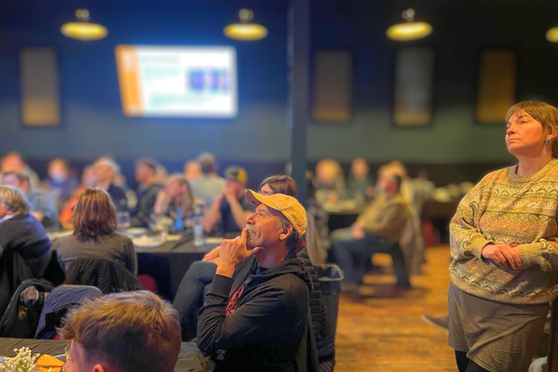 A crowd listens to a lecture at a restaurant venue