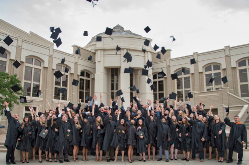 large group of graduates toss their caps