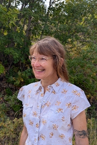 a portrait of Mary Wolf outdoors in front of some foliage