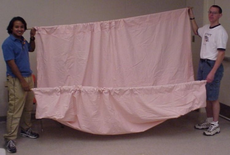 Two guys holding up a large bed sheet