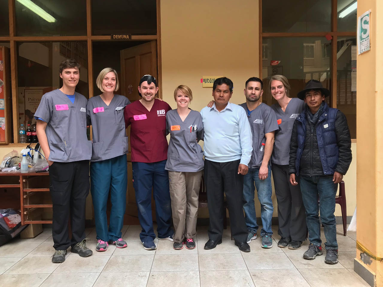 ISU audiology faculty, former students, and current students pose with a patient receiving a hearing aid.