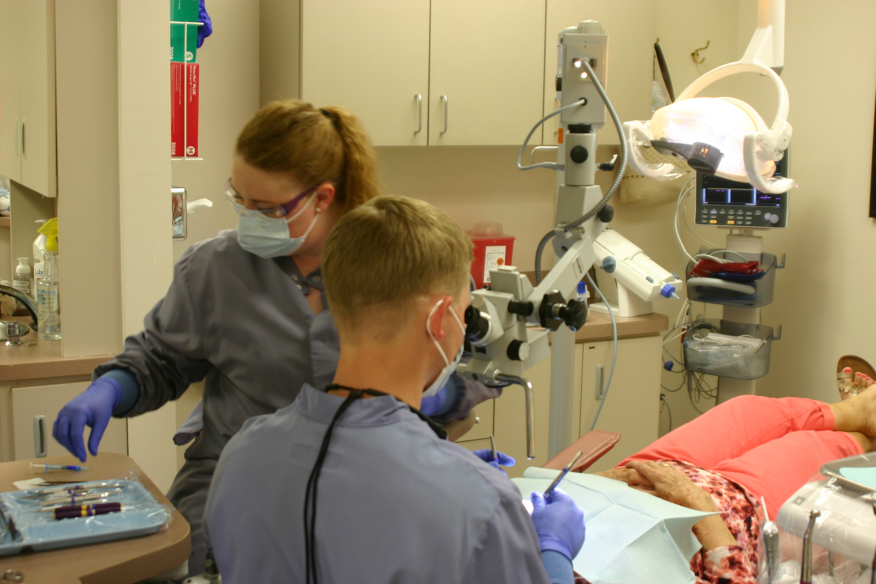 Resident using microscope to treat patient.