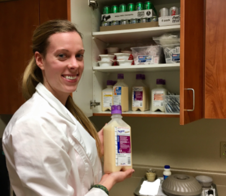 Registered Dietitian holding a TPN formula standing in front of a cabinet full of other TPN formulas