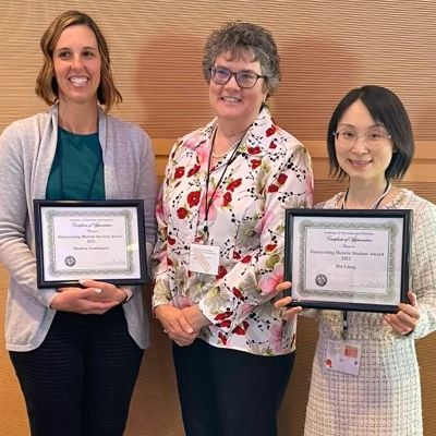 Professor with two students receiving awards at an annual conference