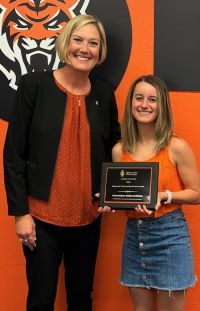 Dean of college of health and student with a plaque award for impactful community service