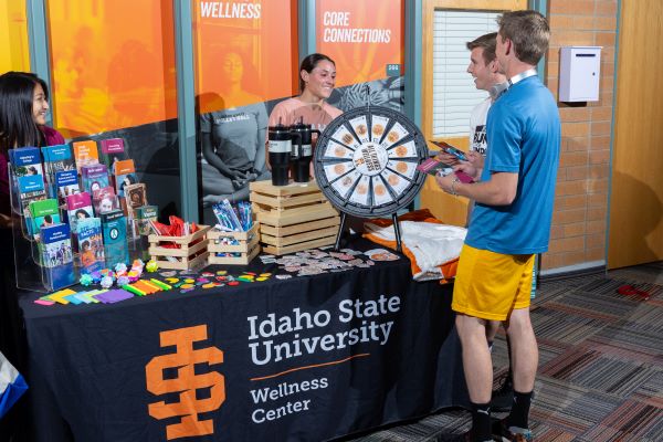 two male students engaging with two female students in front of a wellness center table