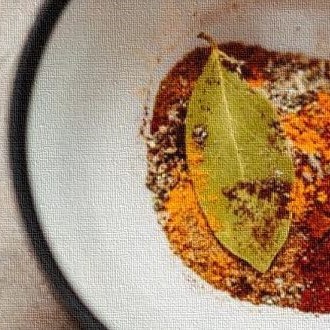 White bowl with paprika, turmeric, and a by leaf