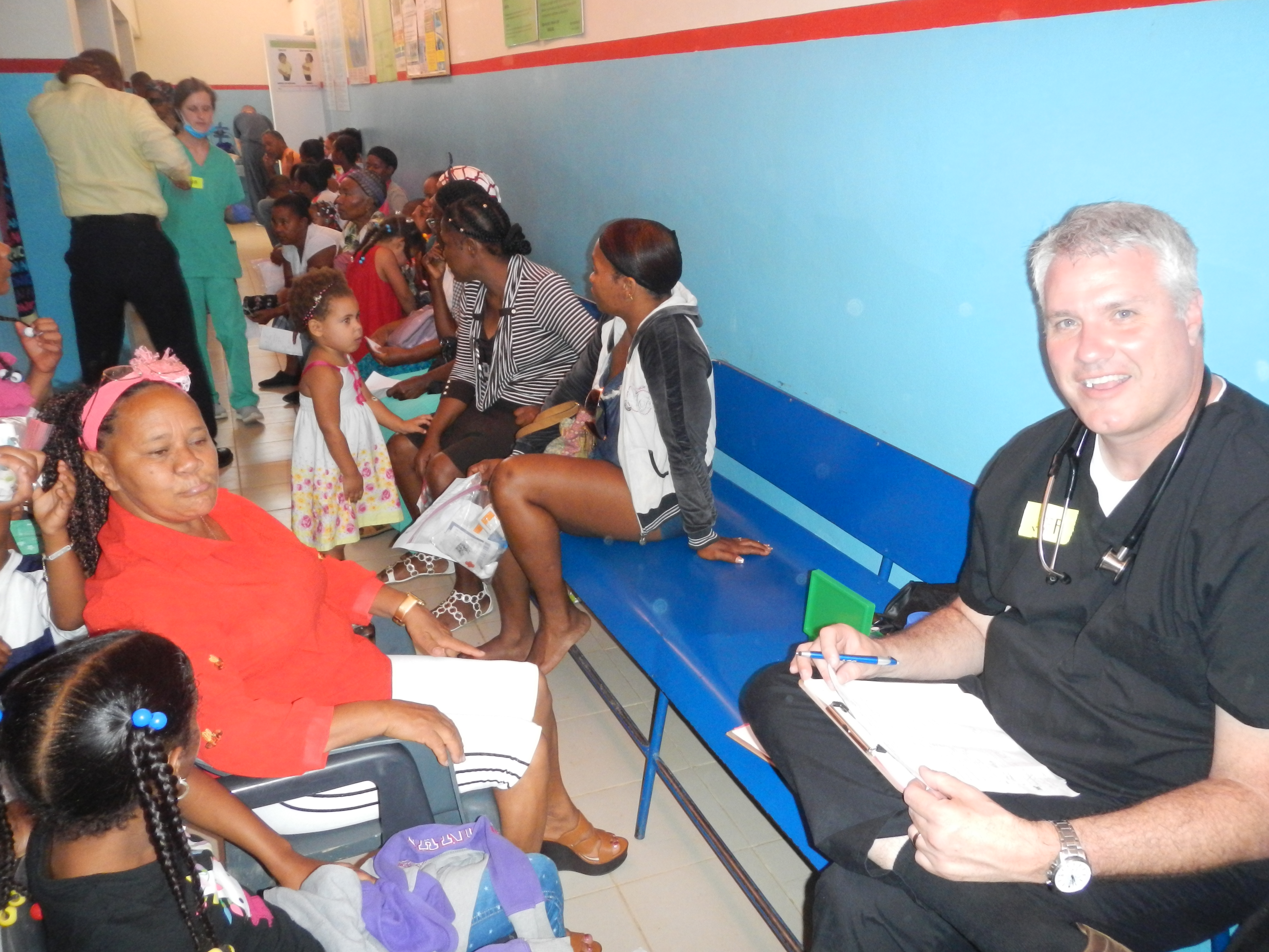 children and adult patients wait in line to be seen by a doctor