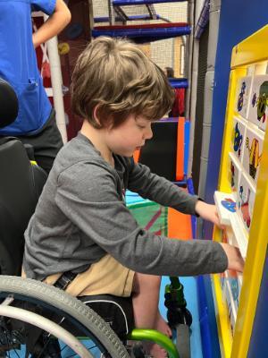 A young boy in a wheelchair plays with a toy in a gymnasium at the ISU FireFlies program