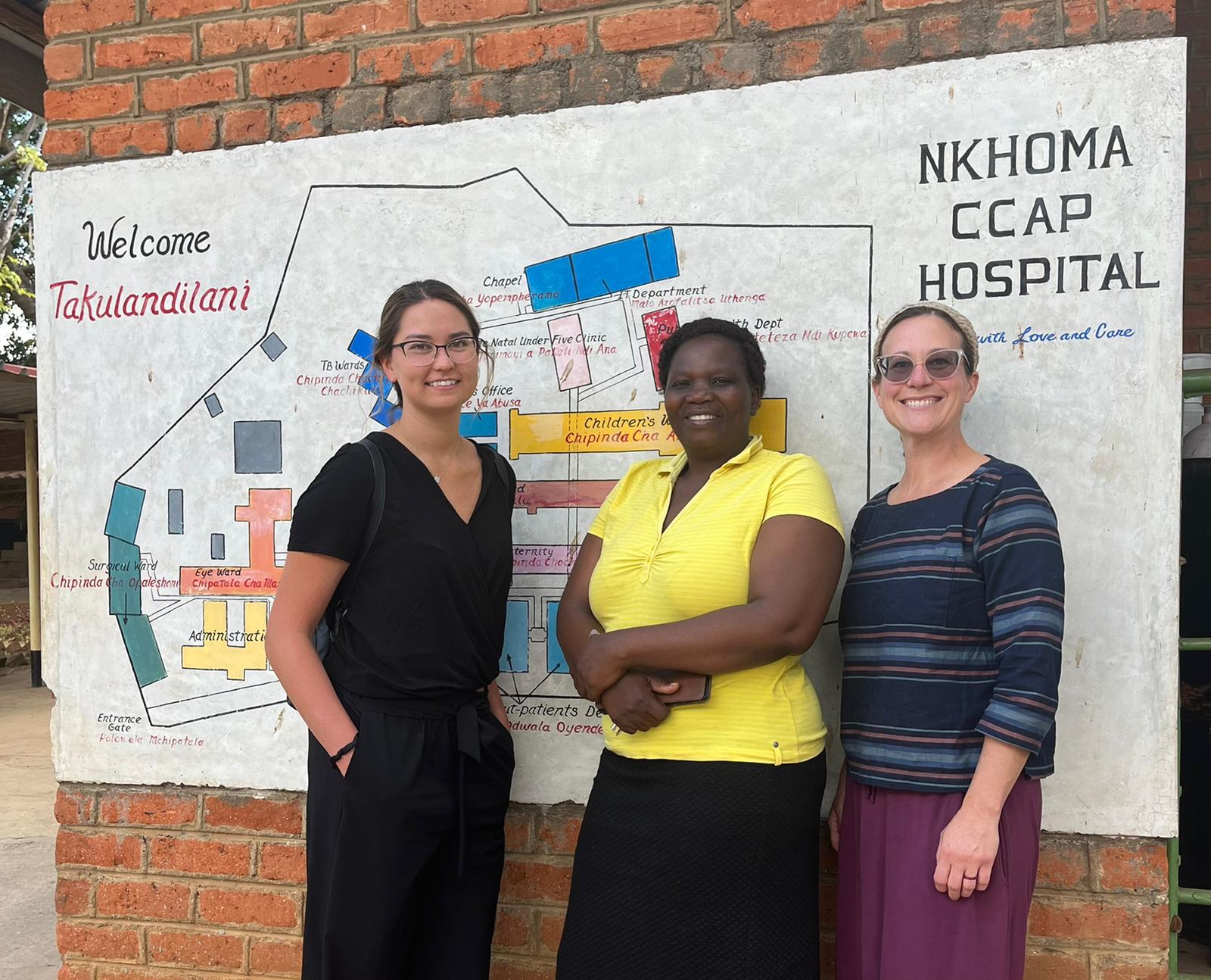 Student and faculty talking with a woman in Malawi