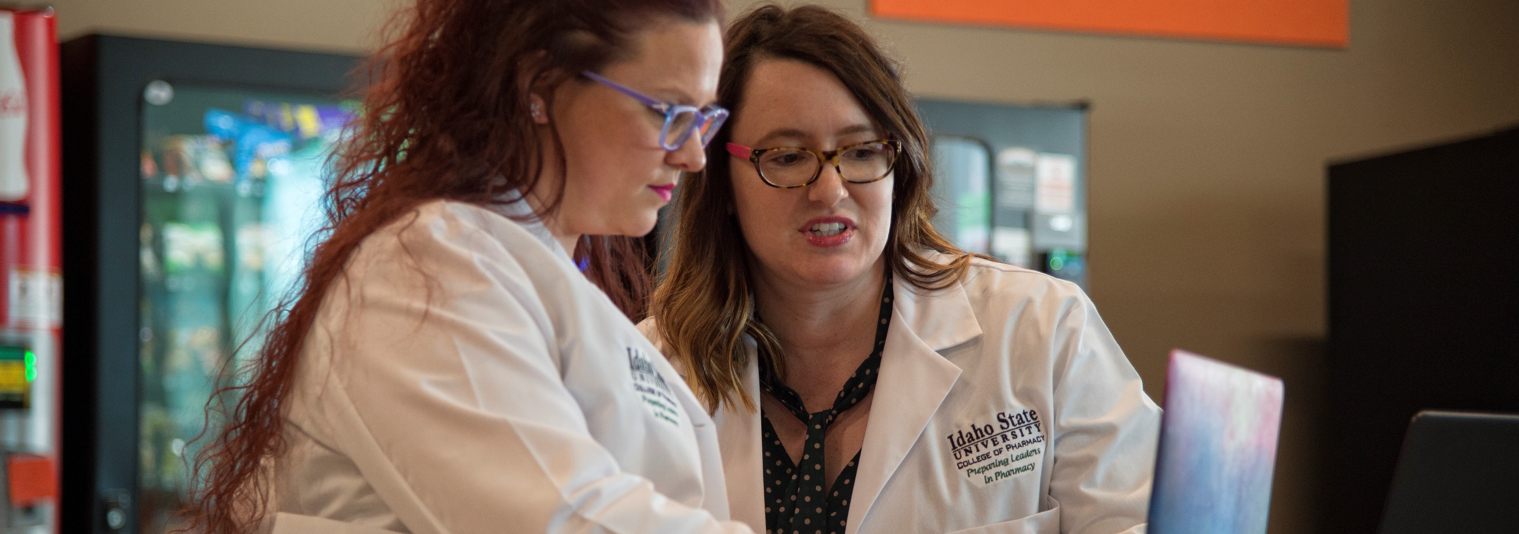 two pharmacy instructors discussing information and looking at a laptop