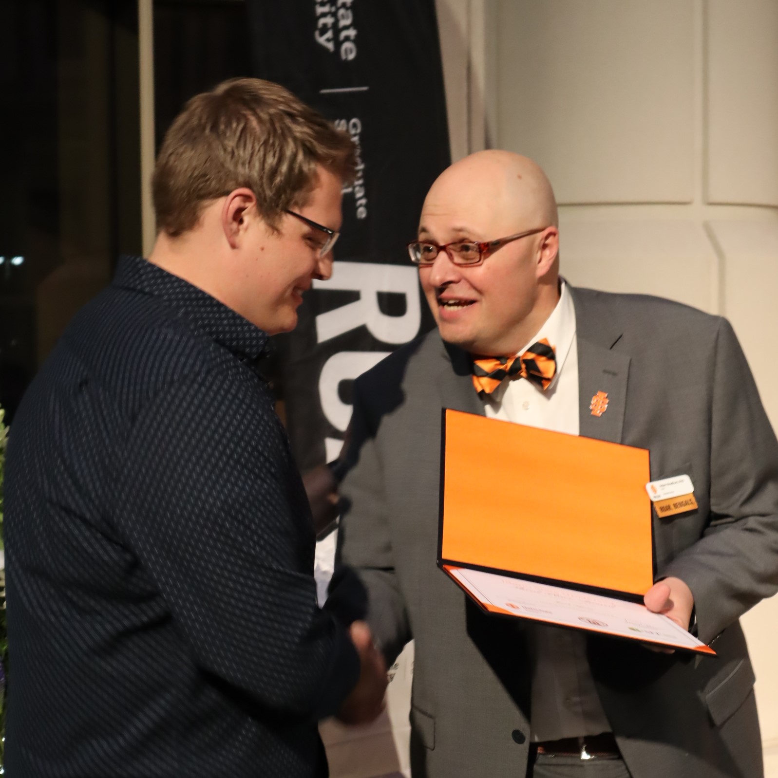 Dr. Adam Bradford shaking hands with a 3MT winner