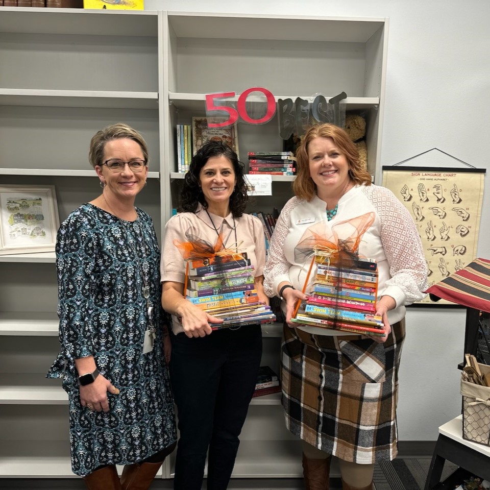 Grad School staff with Connor Academy staff, holding donated books