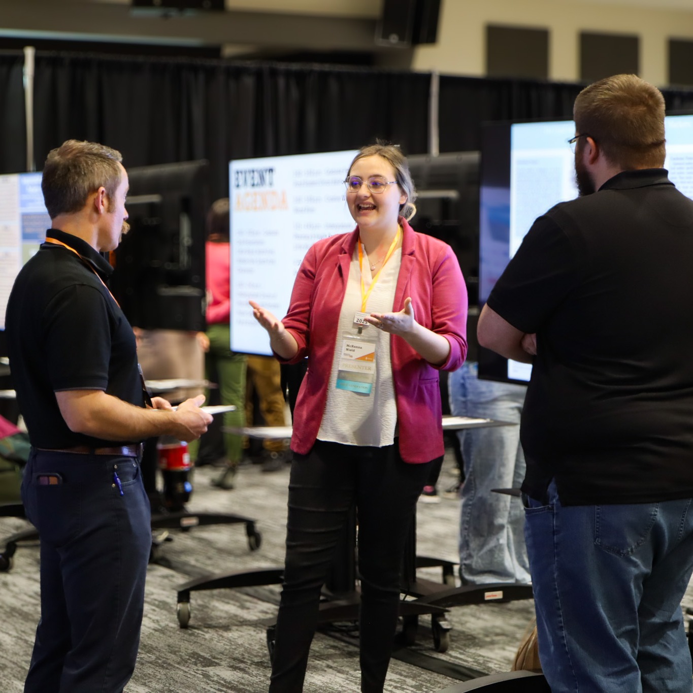 a student presents her poster on a tv to 2 judges