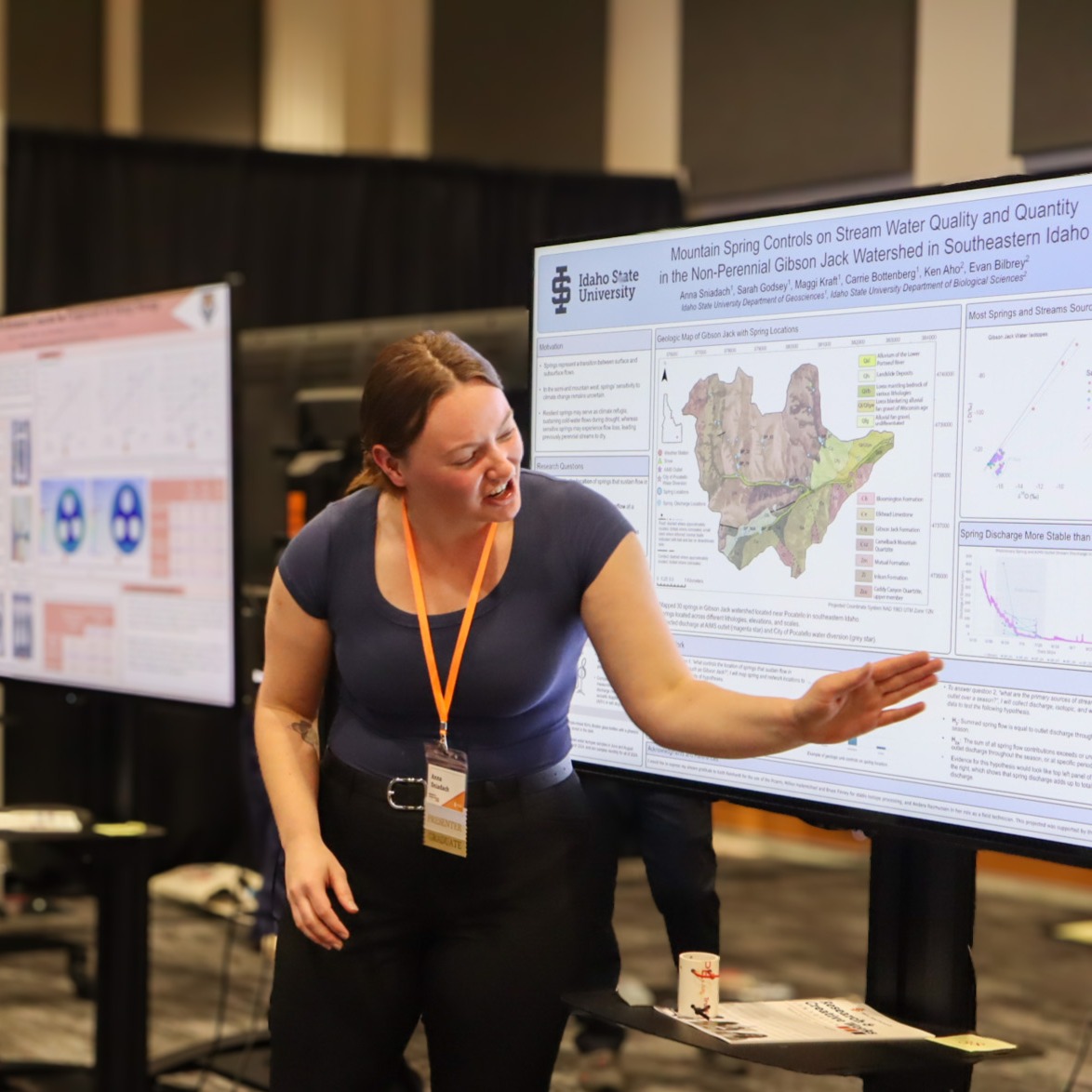 A student gesturing towards her poster on a tv