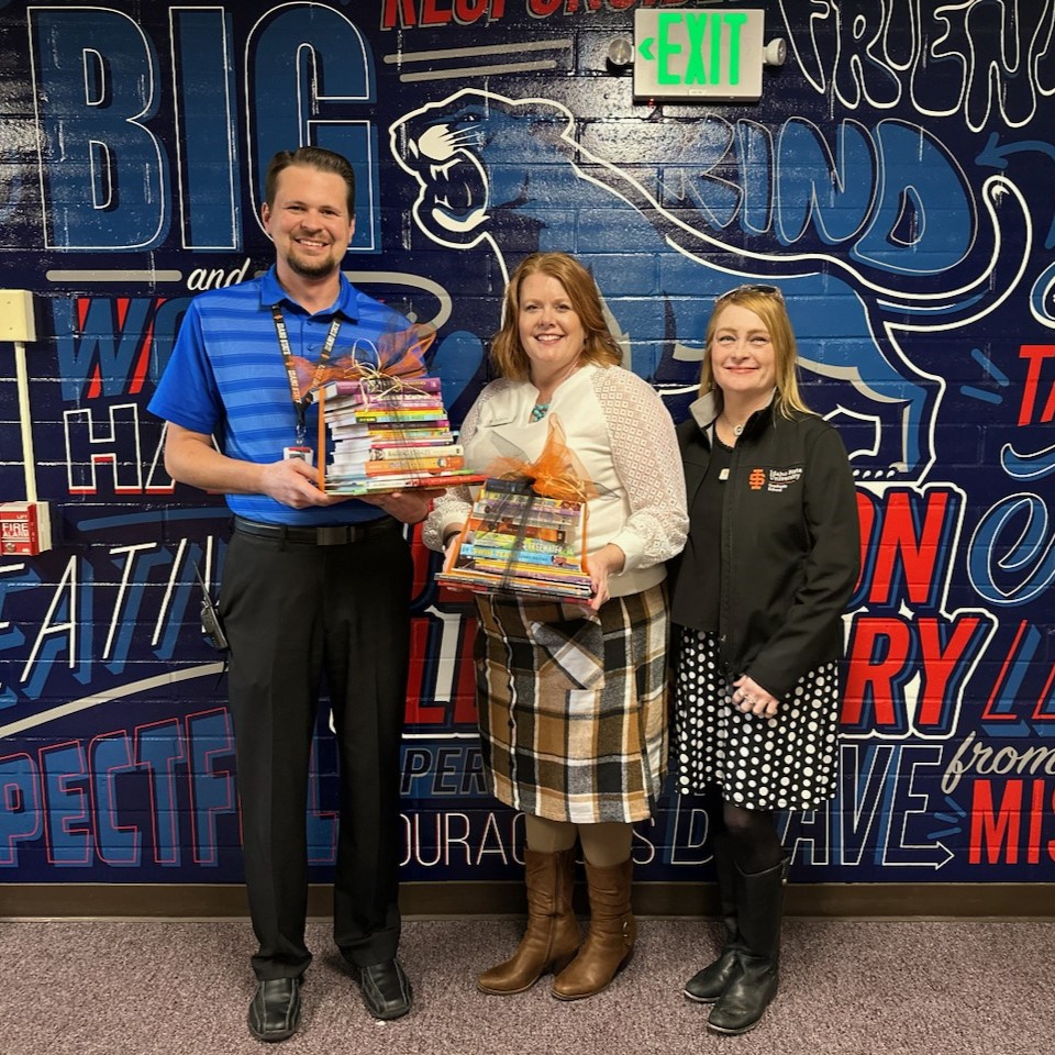 Grad School staff with Jefferson Elementary School staff, holding donated books