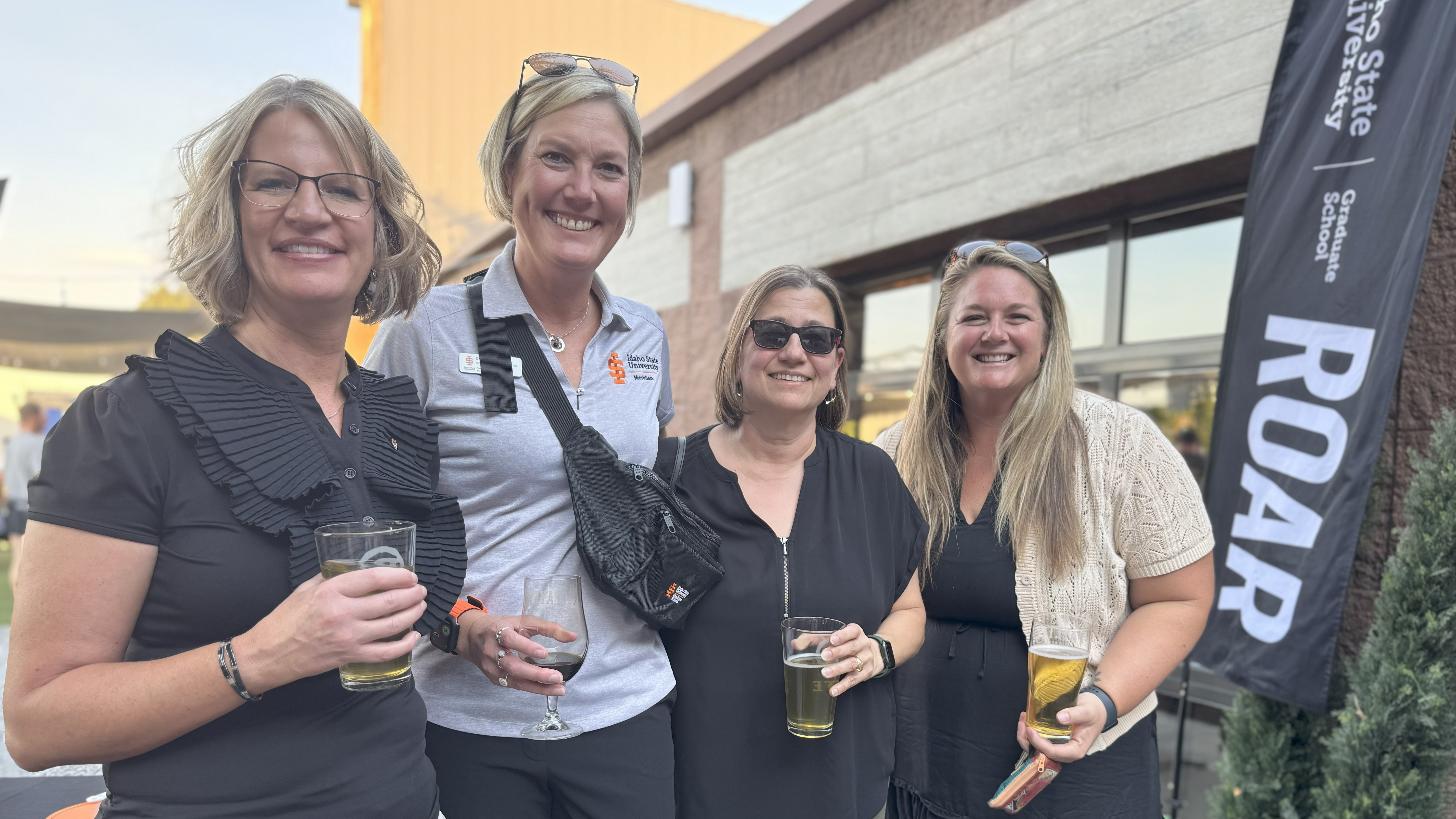 Group of 4 graduate faculty standing together and smiling at the camera