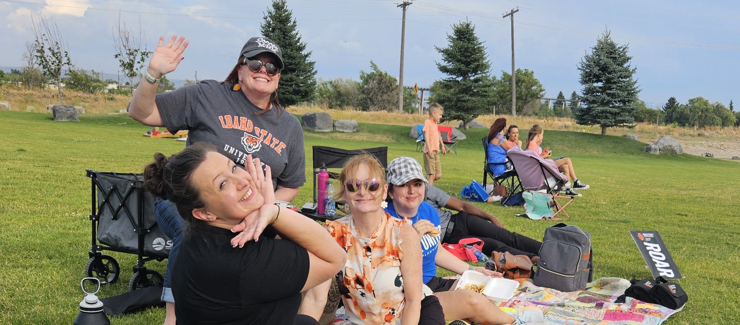 Grad School staff sitting on picnic blankets on the lawn at the Summer Nights 2024 event