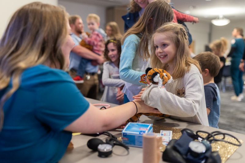Little girl holding a teddy Bengal that she just gave a check up to.