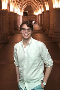 A man smiling in front of an arch