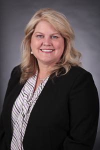 A light skin toned woman with blond hair wearing a white suite and black blazer