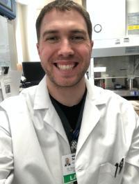 A light skin toned man with wearing a white coat and badge
