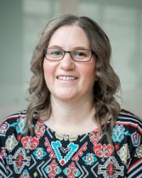 A light skin toned woman wearing a black glasses and a patterned shirt