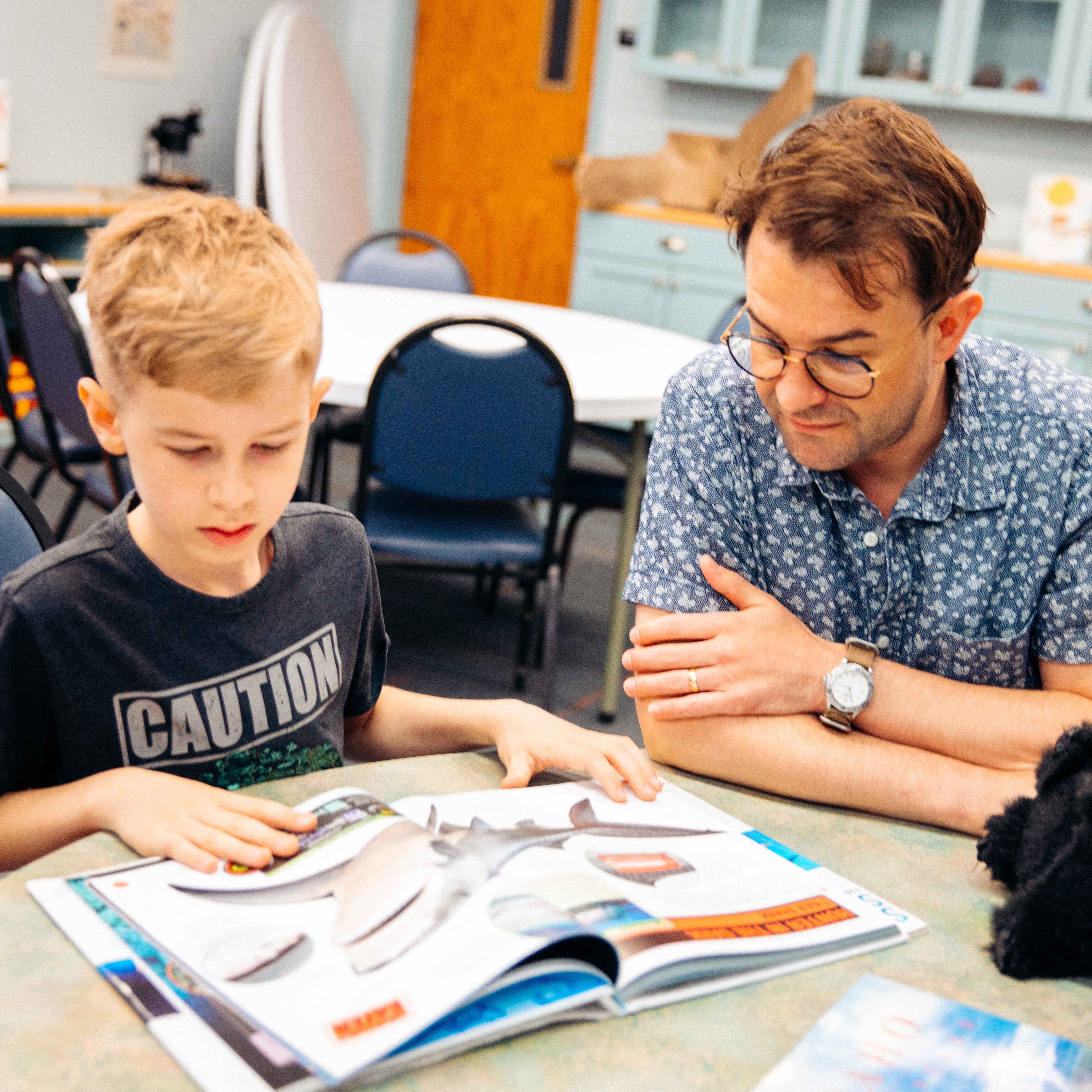 A father and son reading a dinosaur book in the Museum