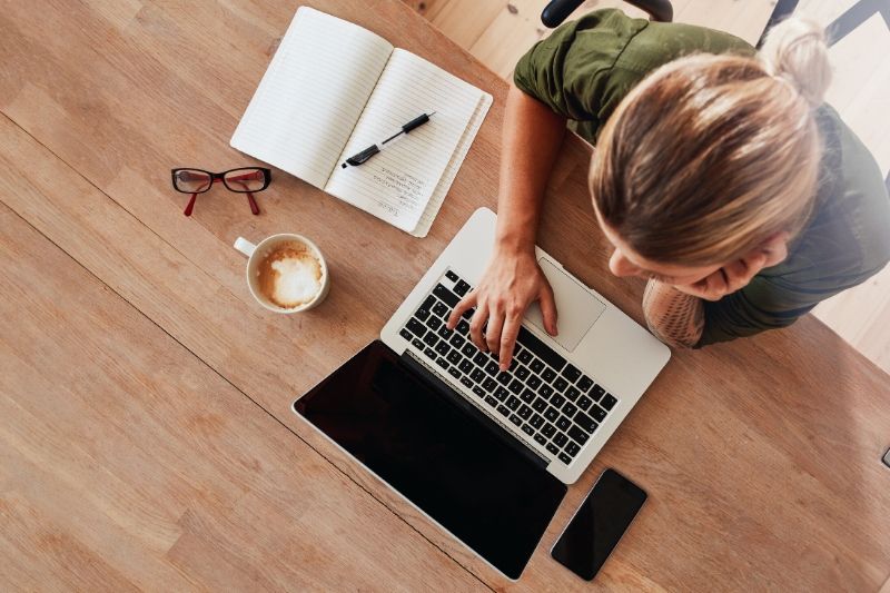 Woman on laptop with coffee and notes