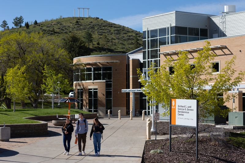 3 students walking with Red Hill and REND building in the background