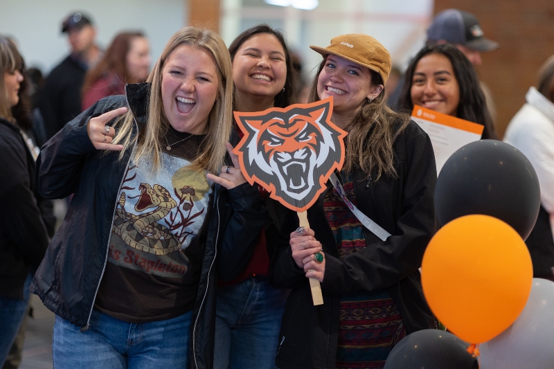 Three students posing with an ISU bengal prompt
