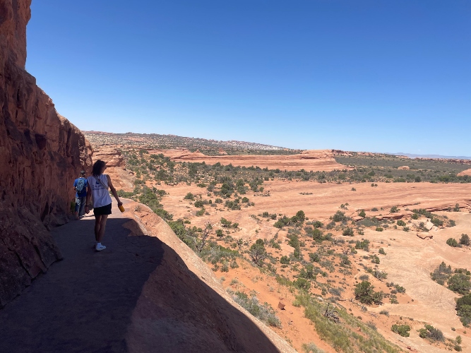 A student walking on red rock trail.
