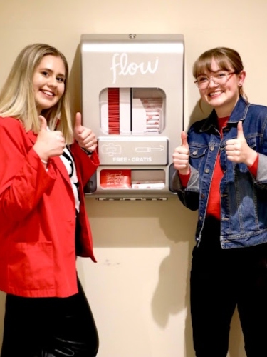 Two students next to a dispenser.