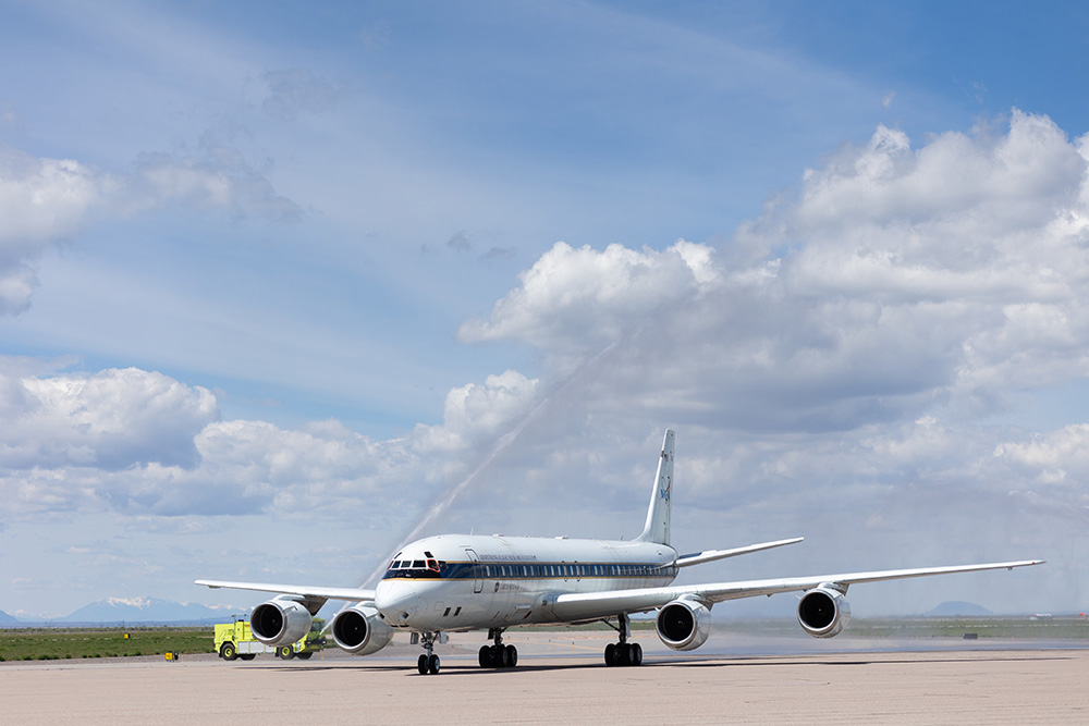 NASA's retired DC-8 research airplanes arrives at the Pocatello Regional Airport with water cannon salute spraying overhead.